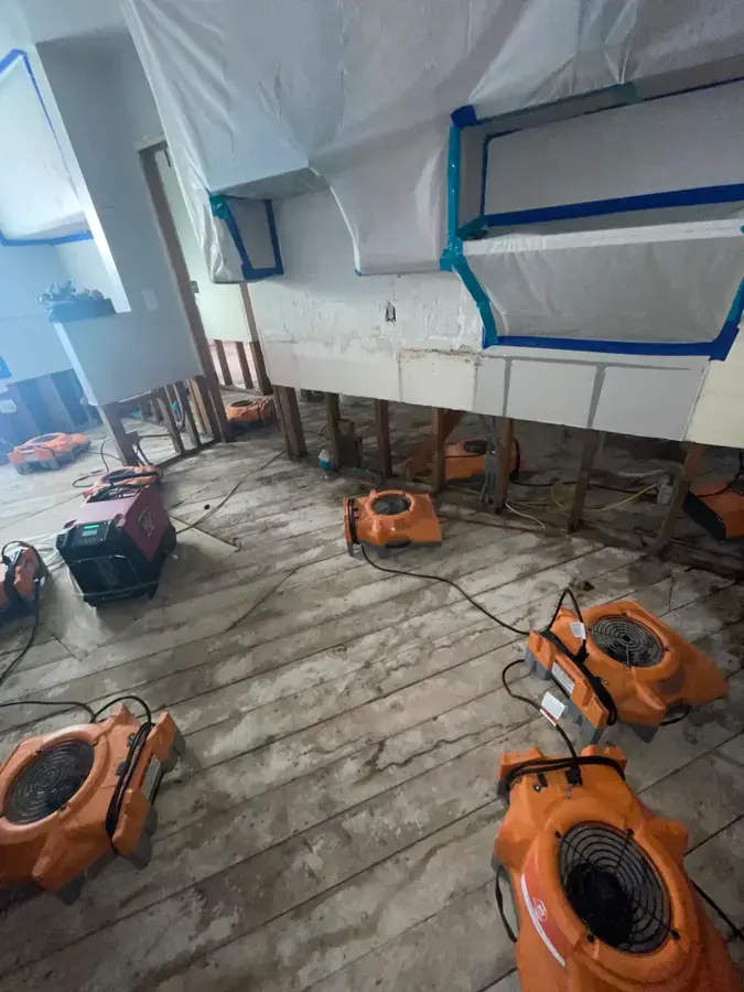 Air movers drying a room with wet flooring removed during water damage restoration in Canoga Park
